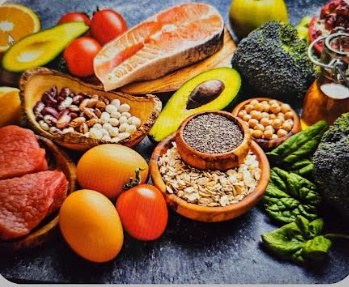 Salmon, lean beef, avocado, oats, beans and greens arranged on a slate surface